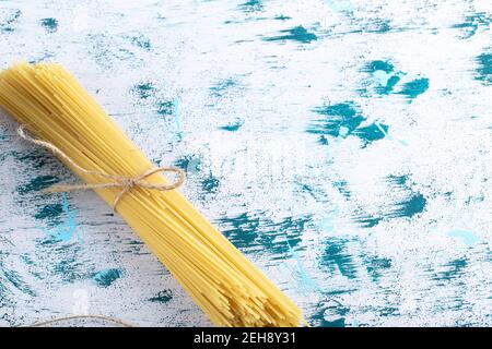 Spaghetti non cotti legati con corda su una superficie colorata Foto Stock