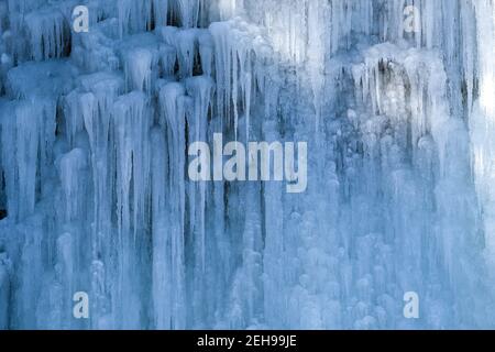 Belle strutture ghiacciate di una cascata ghiacciata, graziose iciclette che formano un interessante modello su una roccia scura, creando un freddo umore di mangia Foto Stock