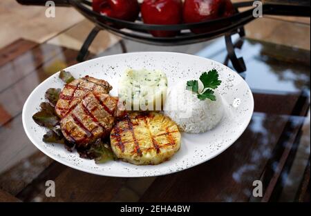 bistecca di maiale alla griglia con purè di patate, riso e una fetta di ananas Foto Stock