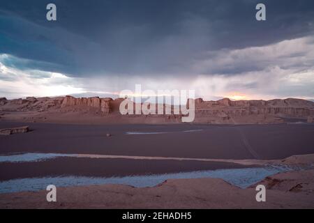 Tempesta con molta pioggia che arriva nel deserto della LUT, Iran, nell'ora d'oro. Le nubi di tempesta si riuniscono mentre l'orizzonte si illumina nel sole che tramonta. Kerman Foto Stock