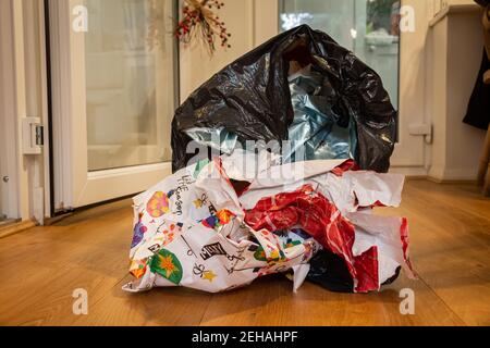 Natale che avvolge lo spreco di carta in un rivestimento del contenitore che giace su un pavimento di legno il giorno di Natale, dopo che i regali erano stati aperti Foto Stock