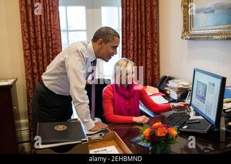 Il presidente Barack Obama e il segretario personale Anita Decker guardano un video dell'ex consigliere David Axelrod che si radica i suoi baffi, nell'ufficio ovale esterno, 7 dicembre 2012. Foto Stock