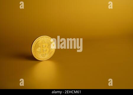 Primo piano di una moneta Bitcoin oro su sfondo giallo. Banner criptovalore con spazio di copia sul lato destro Foto Stock