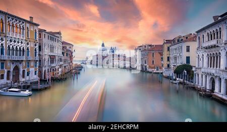 Vista mozzafiato dello skyline di Venezia con il Canal Grande e la Basilica di Santa Maria della Salute in lontananza durante una splendida alba. Foto Stock