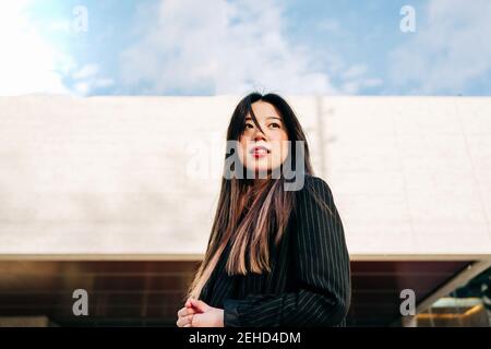 Lunga brunette capelli asian Donna in piedi sulle scale e guardando lontano Foto Stock