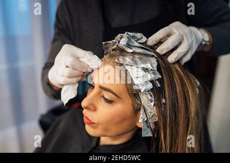 Crop master pettinare trefoli di cliente femminile prima della tintura nella tecnica di balayage Foto Stock