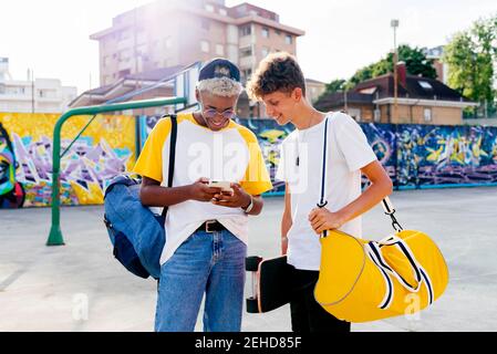 Due ragazzi adolescenti con skateboard e zaino con telefono acceso la strada Foto Stock