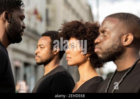 Crop sopportato africano americano maschio giustizia sociale guerrieri con femmina partner in abbigliamento nero in città Foto Stock