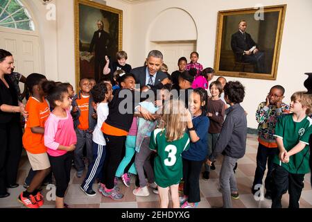 Il presidente Barack Obama abbraccia i bambini che partecipano alla Casa Bianca Bambini sani & Sport sicuro Confusion Summit, nella stanza del Giardino Est della Casa Bianca, 29 maggio 2014. Il presidente ha incontrato il gruppo al chiuso quando il loro evento South Lawn è stato annullato a causa del tempo. Foto Stock