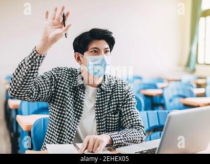 giovane studente che indossa una maschera e studia in classe Foto Stock