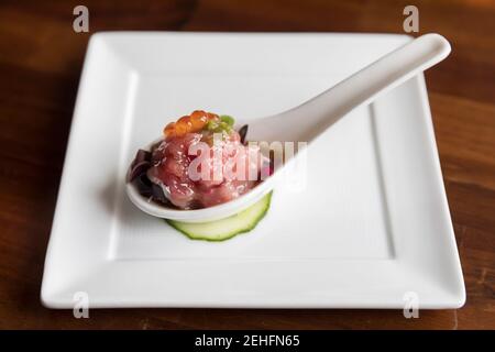 Antipasto di tonno e uova di salmone su cucchiaio bianco e bianco fondo della piastra Foto Stock