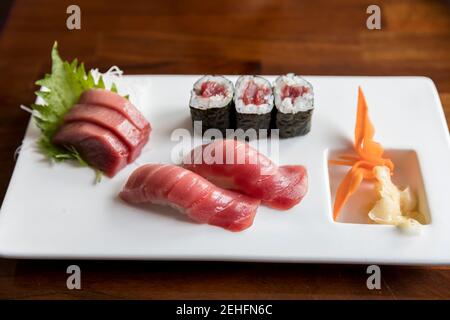 Tonno sashimi e sushi disposti su piatto bianco con colorato guarnire Foto Stock