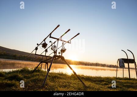 Le avventure di pesca, la pesca alla carpa. Il pescatore, al tramonto, è la pesca con carp fishing tecnica. Campeggio in riva al lago. Foto Stock