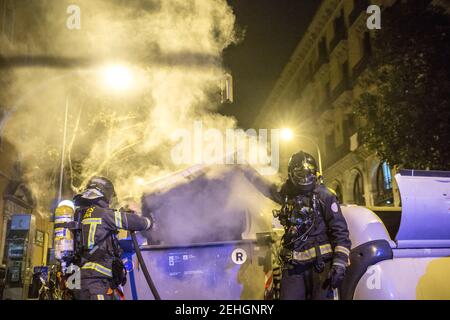 Barcellona, Spagna. 19 Feb 2021. Durante le dimostrazioni, i vigili del fuoco vengono visti spegnere il fuoco dai contenitori dei rifiuti. Quarta notte di proteste e rivolte in risposta all'arresto e alla detenzione del rapper Pablo Hasel accusato di esalare il terrorismo e di insultare la corona dal contenuto dei testi delle sue canzoni. Credit: SOPA Images Limited/Alamy Live News Foto Stock