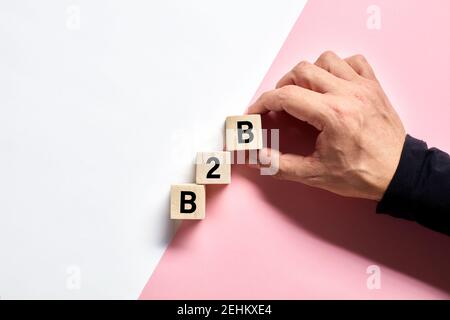 Mano maschile disposizione dei cubi di legno con l'acronimo B2B business to business. Business transaction e concetto di partnership aziendale. Foto Stock