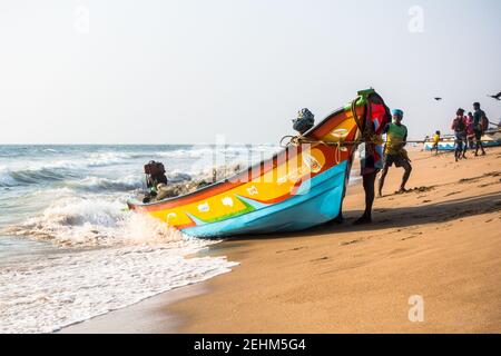 Pescatore che spinge la barca a terra dal mare dopo il ritorno il lavoro di giorno Foto Stock