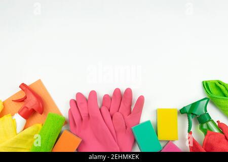 Le gomme rosa, le spugne colorate e le forniture per la pulizia si trovano su un tavolo bianco in cucina Foto Stock