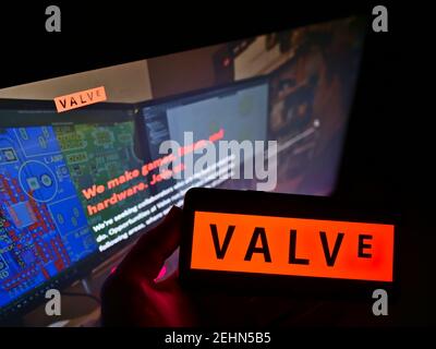 Persona che detiene smartphone con il logo della società di videogiochi statunitense Valve Corporation sullo schermo davanti al sito Web. Mettere a fuoco il display del telefono. Foto Stock