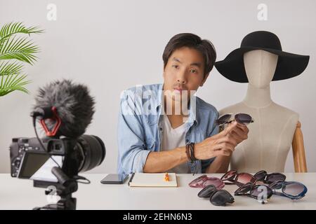 Asian Vlogger o Blogger in Jean Camicie con Mannequins Rivedi occhiali di moda e video di registrazione. Freelance Online Live Streaming con il cliente via Foto Stock