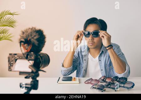 Asian Vlogger o Blogger in Jean Shirts indossare occhiali di moda nero per mostrare il cliente durante la registrazione video. Freelance Online Live Streaming con Cusco Foto Stock