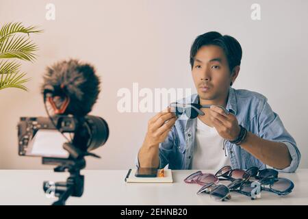 Asian Vlogger o Blogger in Jean Shirts Rivedi occhiali di Moda neri e Video di registrazione. Freelance Online Live Streaming con il cliente tramite Social Me Foto Stock