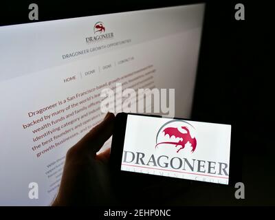 Persona che tiene il telefono mobile con il logo di affari dell'investitore americano Dragoneer Investment Group sullo schermo davanti alla pagina web. Mettere a fuoco il display del telefono. Foto Stock