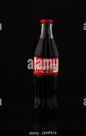 Coca-Cola. Una classica bottiglia di Coca-Cola in vetro con coperchio rosso, isolata su fondo nero. Russia, Nizhny Foto Stock