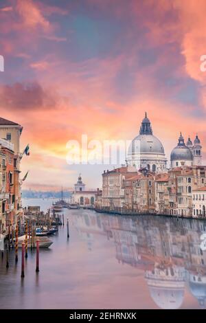 Vista mozzafiato dello skyline di Venezia con il Canal Grande e la Basilica di Santa Maria della Salute in lontananza durante una suggestiva alba. Foto Stock