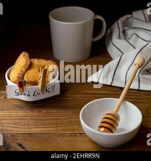 Una piccola ciotola con biscotti e le parole 'buona fortuna !!' su un tavolo di legno e sfondo scuro Foto Stock