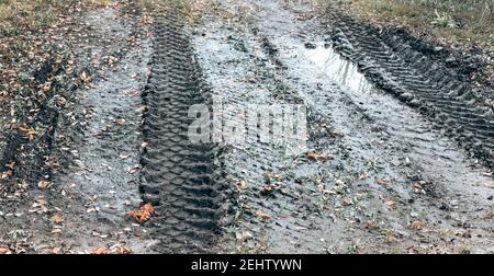 Puddle da una strada sterrata. Paesaggio stradale campagna vuota. Sfondo con contrassegni di strada e pneumatici Foto Stock
