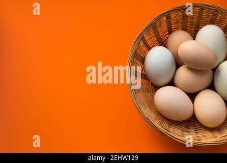 Uova di pollo biologiche in cesto di vimini su sfondo rosso con spazio per la copia. Foto Stock