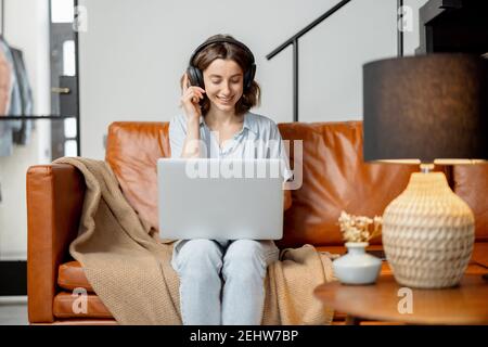 Donna che lavora con notebook e cuffie da casa Foto Stock