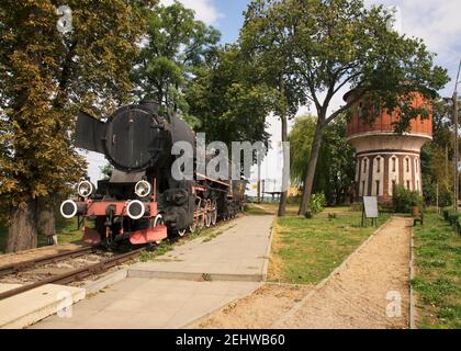 Vecchia locomotiva e torre dell'acqua alla stazione ferroviaria di Jablonowo Pomorskie. Polonia Foto Stock