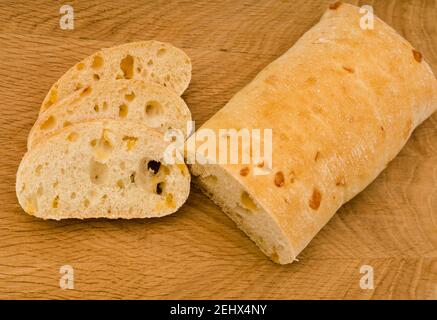 Ciabatta - pane italiano con formaggio tagliato a fette, su tavola di legno Foto Stock