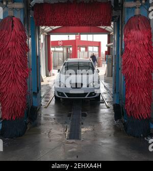 lavaggio auto bianco in autolavaggio automatico con rulli rossi e