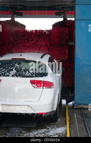 lavaggio auto bianco in autolavaggio automatico con rulli rossi e un sacco di sapone Foto Stock