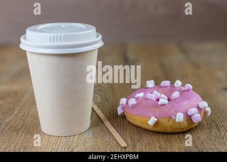 tazza di caffè con ciambella di marshmallow rosa su tavolo di legno Foto Stock