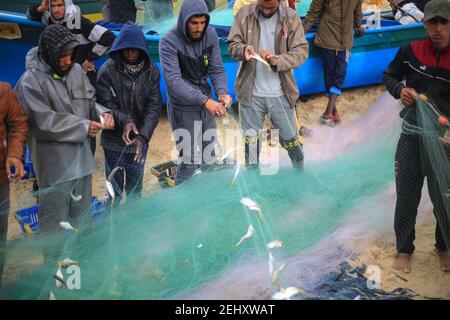 Deir al Balah, Palestina. 19 Feb 2021. I pescatori palestinesi raccolgono i pesci catturati dalle loro reti sulla spiaggia di Deir al-Balah, nella striscia centrale di Gaza, il 19 febbraio 2021 la polizia marittima del movimento di Hamas ha deciso di aprire il mare ai pescatori, a partire da ieri sera, dopo che lo hanno chiuso per tre giorni. (Foto di Mahmoud Khattab/INA Photo Agency/Sipa USA) Credit: Sipa USA/Alamy Live News Foto Stock