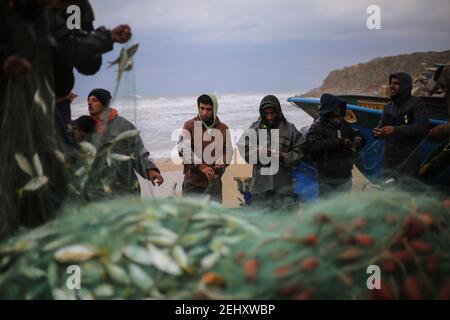 Deir al Balah, Palestina. 19 Feb 2021. I pescatori palestinesi raccolgono i pesci catturati dalle loro reti sulla spiaggia di Deir al-Balah, nella striscia centrale di Gaza, il 19 febbraio 2021 la polizia marittima del movimento di Hamas ha deciso di aprire il mare ai pescatori, a partire da ieri sera, dopo che lo hanno chiuso per tre giorni. (Foto di Mahmoud Khattab/INA Photo Agency/Sipa USA) Credit: Sipa USA/Alamy Live News Foto Stock