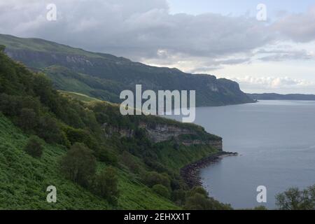 Immagine paesaggistica di una costa verde incontaminata al largo dell'isola di raasay. Una remota posizione scozzese al tramonto con un cielo leggermente nuvoloso e un mare calmo. Foto Stock