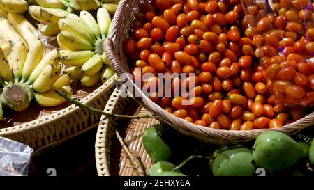 Frutta e verdura su stalla rustica. Frutta e verdura fresche mature assortite e collocate sul rustico stand orientale nel mercato. Mango verde, pomodori e. Foto Stock