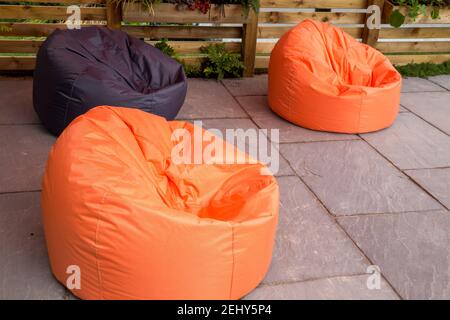 Grandi beanbag arancioni e nere sedute su una pietra Patio lastricato Inghilterra GB UK Foto Stock