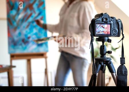 Artista live streaming dal suo studio. Artista femminile che registra il suo video tutorial sulla pittura d'arte. Donna freelance che condivide online il suo lavoro Foto Stock