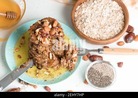 frittelle fatte in casa con semi di chia, mandorle, prugne e datteri, condite con miele e noci schiacciate su sfondo scuro. colazione dietetica Foto Stock