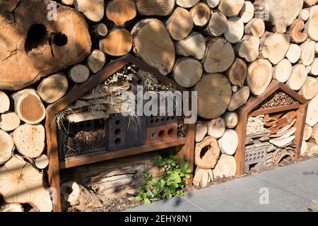 giardino con pareti in tronchi con insetto alberghi habitat di insetto motel per pollinatori fatto con vecchi mattoni, ramoscelli, piastrelle, cartone Foto Stock