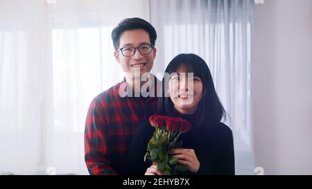 Felice giovane coppia asiatica abbracciando. Donna con rose rosse. Foto di alta qualità Foto Stock