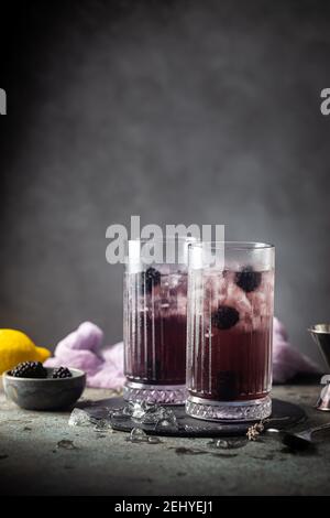 Rinfrescare BlackBerry Lemonade con ghiaccio in bicchieri di cristallo su sfondo grigio Foto Stock