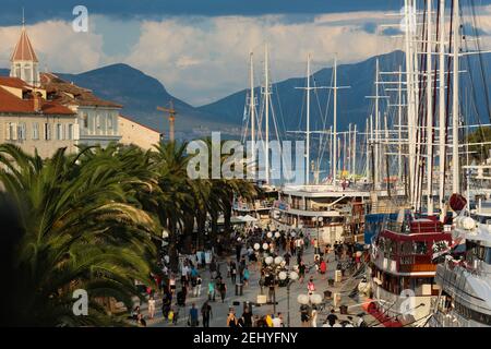 Trafficata strada della città di Trogirs Boat Port con Montagne sullo sfondo Foto Stock