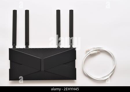 Moderno router wi-fi 6 nero su sfondo bianco con cavo ethernet Foto Stock