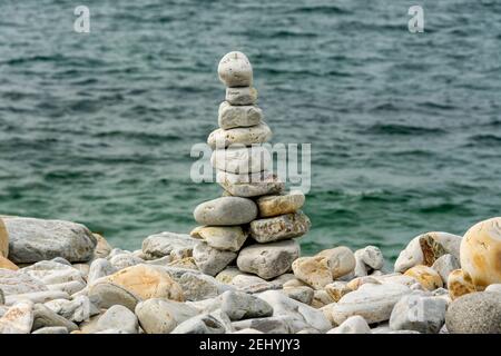 Torre di pietra creata bilanciando ciottoli su una costa tranquilla durante le ore diurne Foto Stock